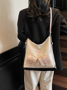 Sac fourre-tout chic crème et rose avec chaîne argentée porté par un mannequin