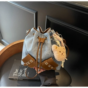 Detail der Vintage Denim Bucket Bag mit braunem Lederbesatz und Plüschbär-Anhänger