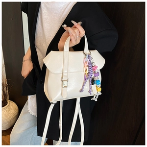 Detail view of cream white leather bucket bag with colorful bead charm and silver clasp