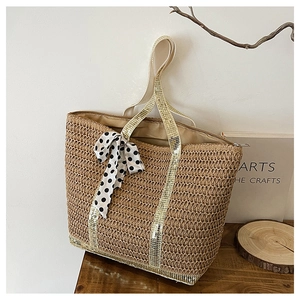 Detail of hand-woven straw tote bag with polka dot bow and gold sequin handles