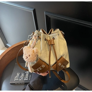 Detailansicht der Canvas-Beuteltasche mit braunem Lederbesatz und Plüschbär-Anhänger