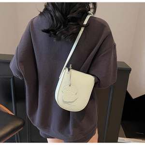 Détail du sac seau vert menthe en cuir grainé avec un charmant pendentif en chien