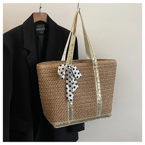 Détail du sac en paille avec anses pailletées dorées et foulard à pois noir et blanc