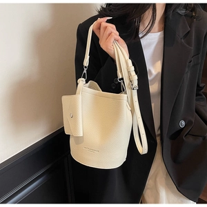 Close-up of beige lychee texture bucket bag with detachable small coin purse detail