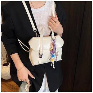 Detail of white leather handbag with colorful braided chain on a female model