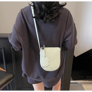 Détail du sac selle vert menthe en cuir litchi avec breloque chien et texte