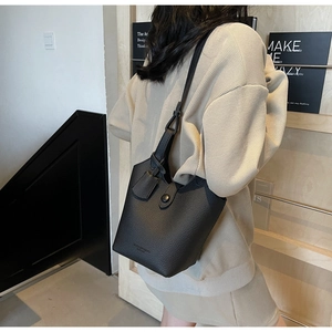 Close-up of black lychee grain leather bucket bag with silver hardware and logo detail