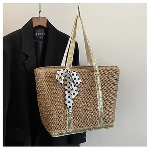 Détail du sac cabas en paille avec anses dorées et foulard en soie chic à pois