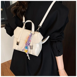 Close-up of cream PU leather mini backpack worn by model featuring colorful strap charm