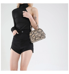 Detail of snake skin print shell bag with round handles shown on a model