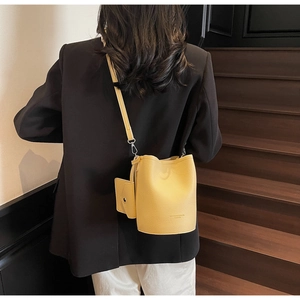 Detail of ginger yellow bucket bag in lychee texture leather with matching card pouch