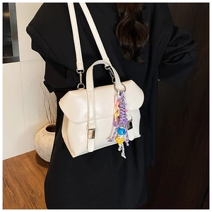 Detail of cream leather bucket bag with colorful beaded charm and crossbody strap