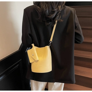 Detail of yellow pebbled leather bucket bag with hanging flap pouch and silver hardware