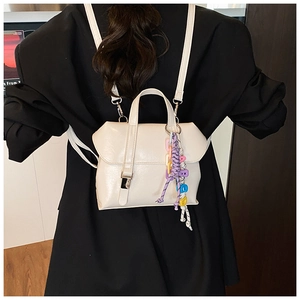 Detail view of cream white PU leather backpack featuring metal buckle and colorful bead charm