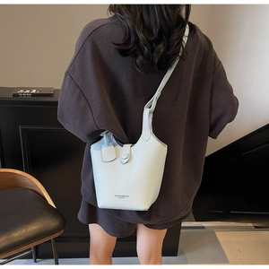 Detail of light blue bucket bag with lychee grain leather and shoulder strap on model