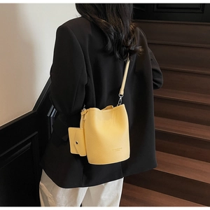 Yellow pebbled leather bucket bag with matching coin purse shown on model shoulder