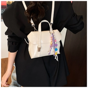 Detail view of a cream leather backpack with fashion beaded charm and adjustable strap