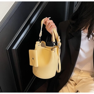 Detail of yellow pebbled leather bucket bag with a mini pouch and adjustable strap