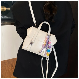 Detail of white PU leather crossbody bag with colorful woven letter charm on strap