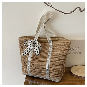 Détail du sac cabas en paille avec bandoulières à paillettes et un nœud à pois élégant