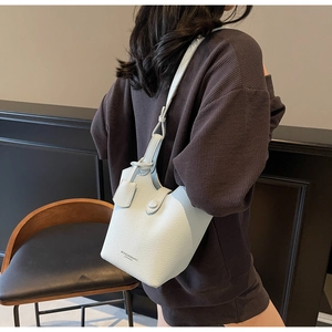 Detail view of light blue lychee pattern bucket bag with shoulder strap and button closure