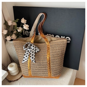 Detail of hand-woven straw tote bag with vibrant orange sequin straps and polka dot bow
