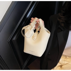 Close-up of premium beige bucket bag with lychee grain leather and metallic buckle
