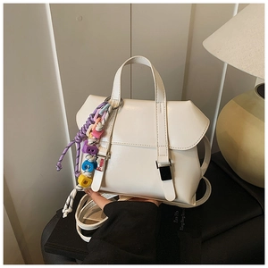 Detail of white leather handbag with metal buckle and colorful woven letter charm