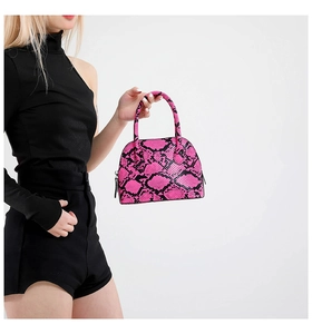 Detail of bright pink snakeskin shell bag with metal zipper and rounded top handle