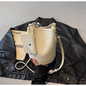 Detail of beige litchi grain bucket bag with mini envelope pouch on black leather