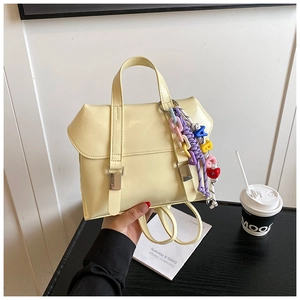 Detail of a creamy yellow faux leather backpack with colorful charms and double strap