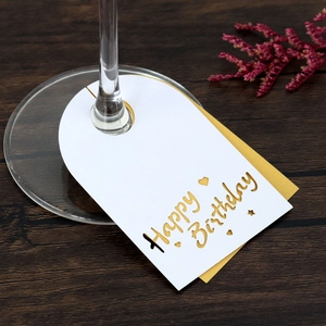 Detalle de tarjetas Happy Birthday para copas de vino con diseño de papel dorado