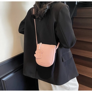 Détail du sac selle rose en cuir texturé avec un joli pendentif en forme de chien