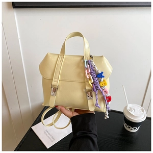 Detail of light yellow PU leather backpack with silver buckles and colorful charm