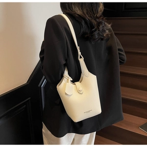 Close-up of cream lychee leather bucket bag with MUONJIN&BAGS logo on a model
