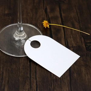 Close-up of white U-shaped kraft paper place card with hanging hole on wood surface