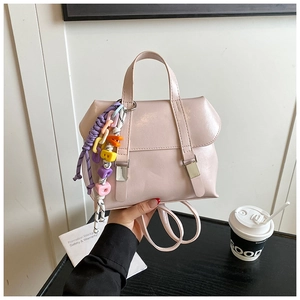 Detail of pink PU backpack with decorative metal buckles and a colorful letter charm
