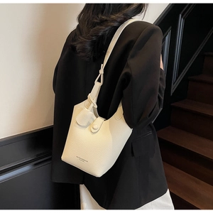 Detail of cream white bucket bag with pebble leather texture and knot strap design