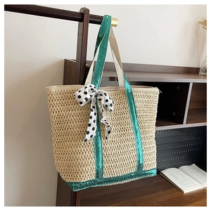 Detail of woven straw tote bag featuring green sequins and a polka dot ribbon bow