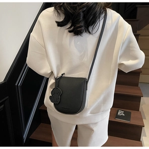 Détail du sac selle noir en cuir grainé avec breloque chiot et fermeture éclair