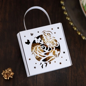 Detail of laser-cut butterfly and rose pattern on white wedding favor box with handle