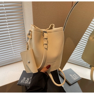 Close-up of beige lychee texture bucket bag with matching mini pouch and gold logo
