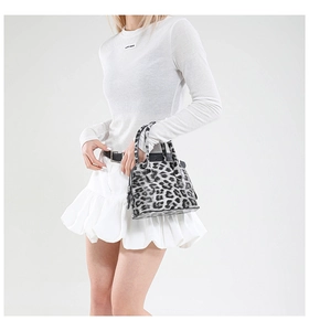 Detail of a mini leopard print shell bag with top handles shown on a model