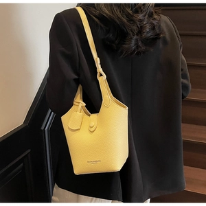 Detail shot of bright yellow lychee grain leather bucket bag worn by a model