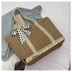 Close-up of straw woven tote bag with gold sequins and a polka dot silk bow charm