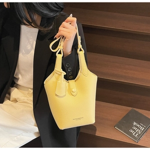 Close-up of bright yellow bucket bag with lychee grain leather texture and metallic logo