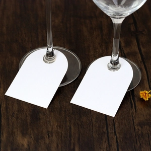 Close-up of arched white paper place cards with round holes for wine glass stem decoration