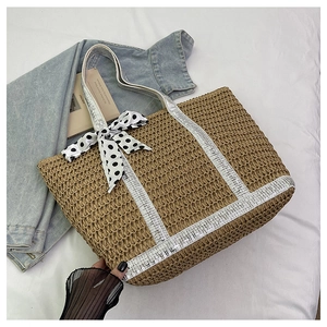 Close-up of straw woven tote with H-shaped sequins and a black and white polka dot bow