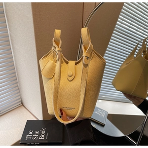 Detailed view of yellow bucket bag with lychee grain texture and metal magnetic clasp