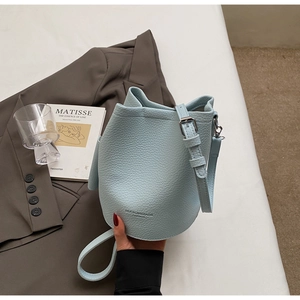 Detail view of the light blue bucket bag showing soft lychee grain texture and metal buckle